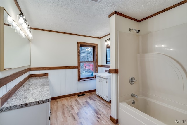 bathroom with a textured ceiling, hardwood / wood-style flooring, vanity, shower / tub combination, and crown molding