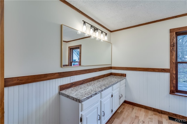 bathroom with ornamental molding, a wealth of natural light, a textured ceiling, and hardwood / wood-style flooring