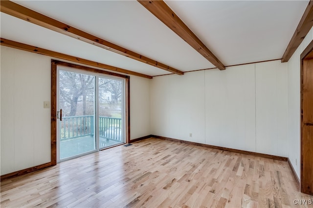 empty room featuring light hardwood / wood-style floors and beamed ceiling