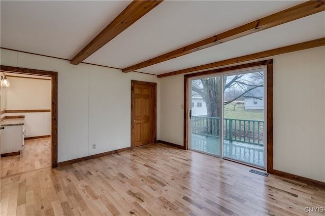 unfurnished room with light wood-type flooring and beam ceiling