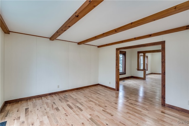 empty room featuring beamed ceiling and light hardwood / wood-style flooring