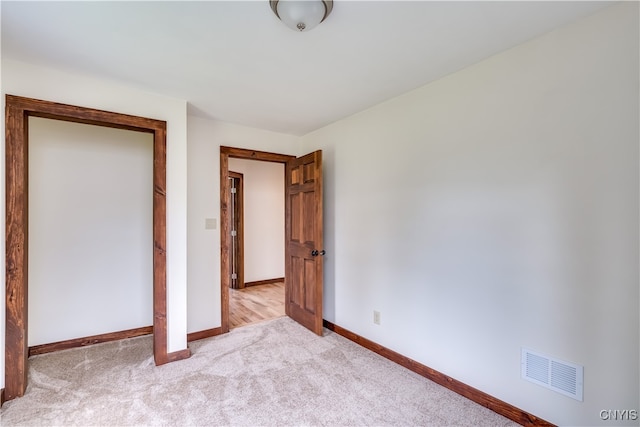 unfurnished bedroom featuring light carpet and a closet