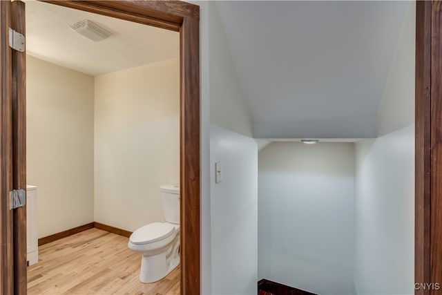 bathroom featuring hardwood / wood-style floors, lofted ceiling, and toilet