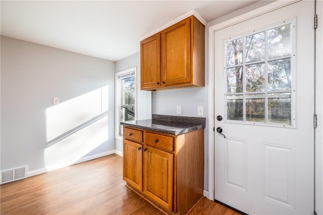 doorway to outside with baseboards, visible vents, and light wood-type flooring