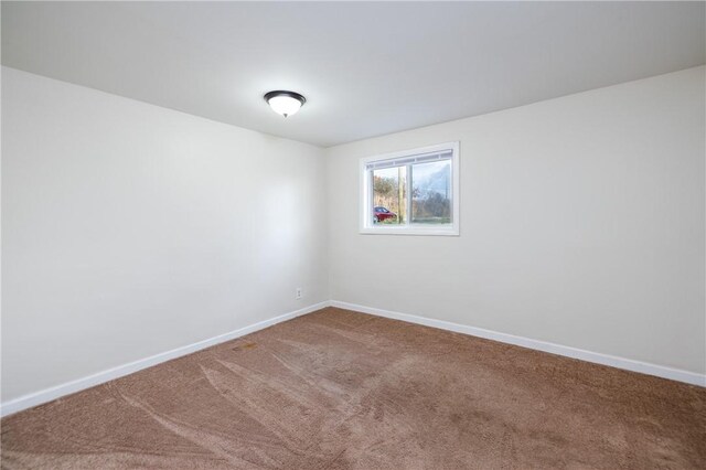 carpeted spare room featuring baseboards