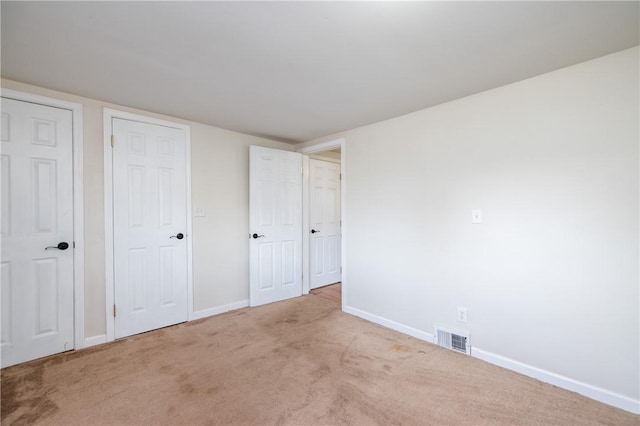 unfurnished bedroom featuring carpet, visible vents, and baseboards