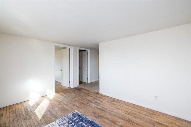spare room featuring wood-type flooring and baseboards