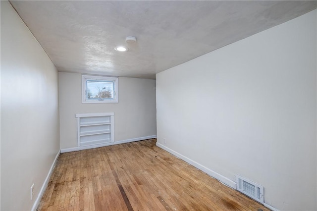 additional living space featuring built in features, light wood finished floors, baseboards, visible vents, and recessed lighting