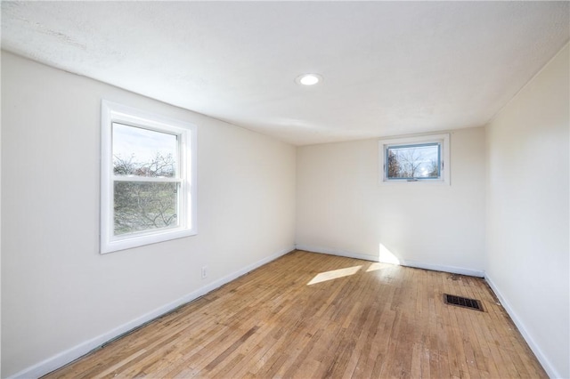 unfurnished room featuring hardwood / wood-style floors, baseboards, visible vents, and recessed lighting
