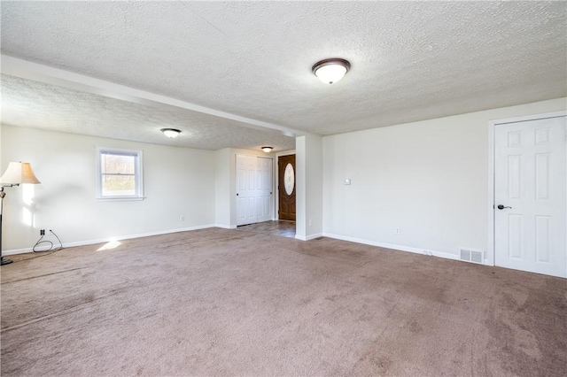 spare room with baseboards, visible vents, carpet, and a textured ceiling