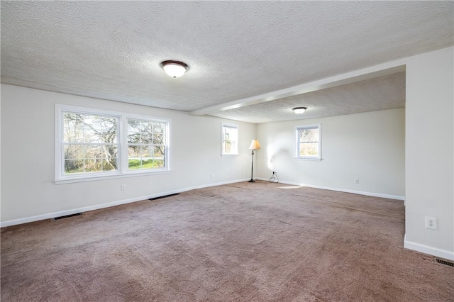 carpeted empty room featuring baseboards, a textured ceiling, and visible vents