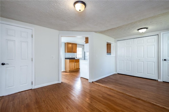 interior space featuring baseboards, wood finished floors, and a textured ceiling