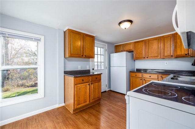 kitchen with brown cabinetry, white appliances, and light wood-style floors