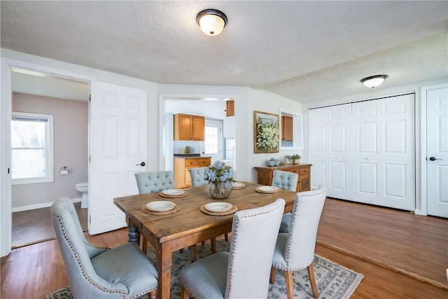 dining space with light wood-style flooring, a wealth of natural light, and baseboards