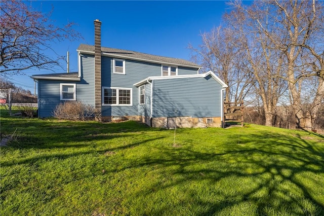 rear view of property with a chimney and a yard