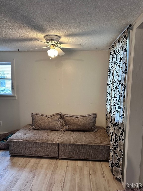 living room featuring hardwood / wood-style flooring, ceiling fan, and a textured ceiling