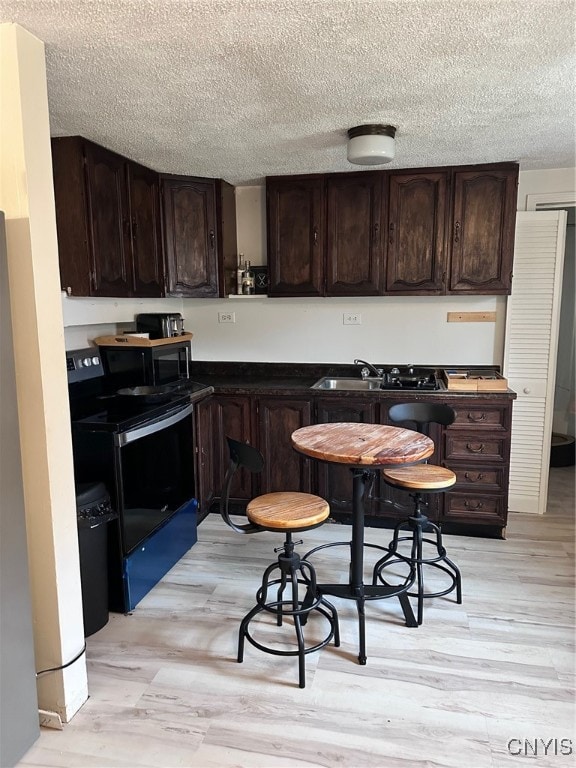 kitchen featuring dark brown cabinetry, black appliances, a textured ceiling, sink, and light wood-type flooring