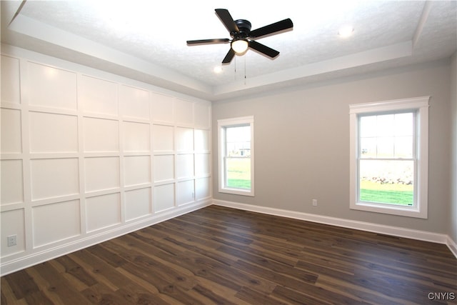 empty room featuring ceiling fan, dark hardwood / wood-style floors, a textured ceiling, and a raised ceiling