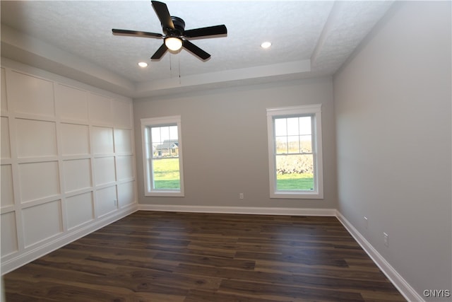 spare room with dark wood-type flooring, ceiling fan, a textured ceiling, and a tray ceiling