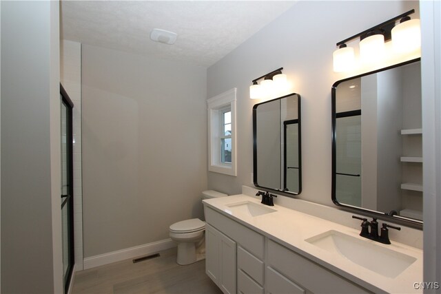 bathroom featuring hardwood / wood-style floors, a shower with shower door, vanity, and toilet