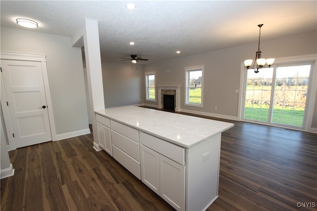 kitchen featuring dark hardwood / wood-style floors, white cabinetry, decorative light fixtures, and ceiling fan with notable chandelier