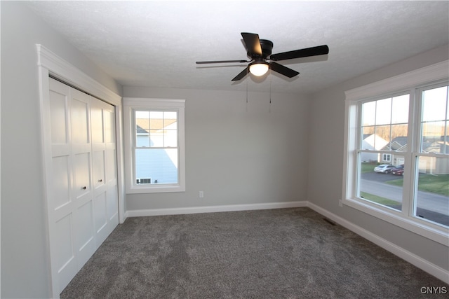 empty room with ceiling fan, a textured ceiling, and dark carpet