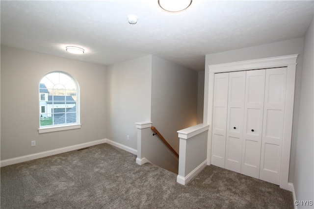 interior space featuring a textured ceiling and dark colored carpet