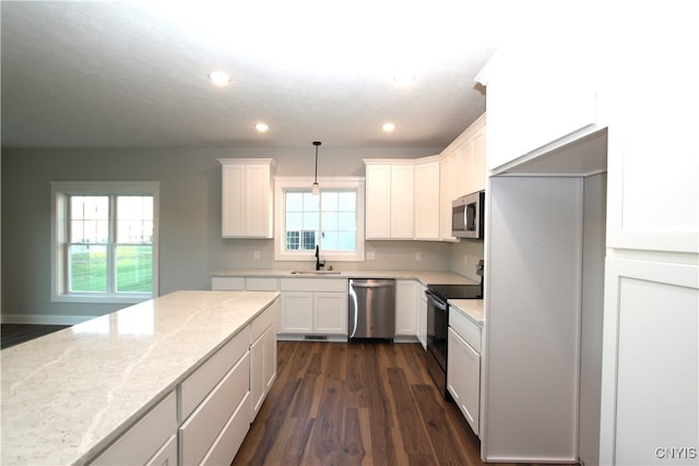 kitchen featuring stainless steel appliances, white cabinets, dark hardwood / wood-style floors, light stone countertops, and pendant lighting