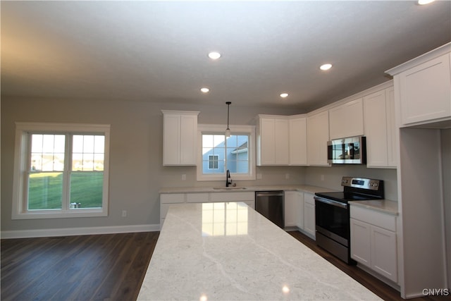 kitchen featuring a wealth of natural light, appliances with stainless steel finishes, sink, and light stone counters