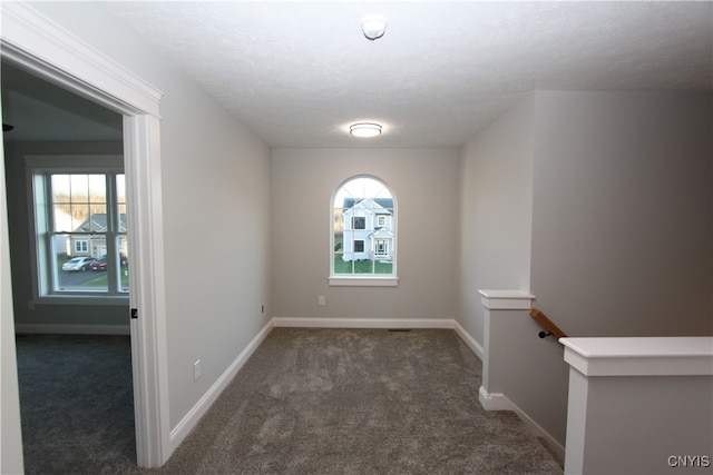 spare room with dark colored carpet and a textured ceiling