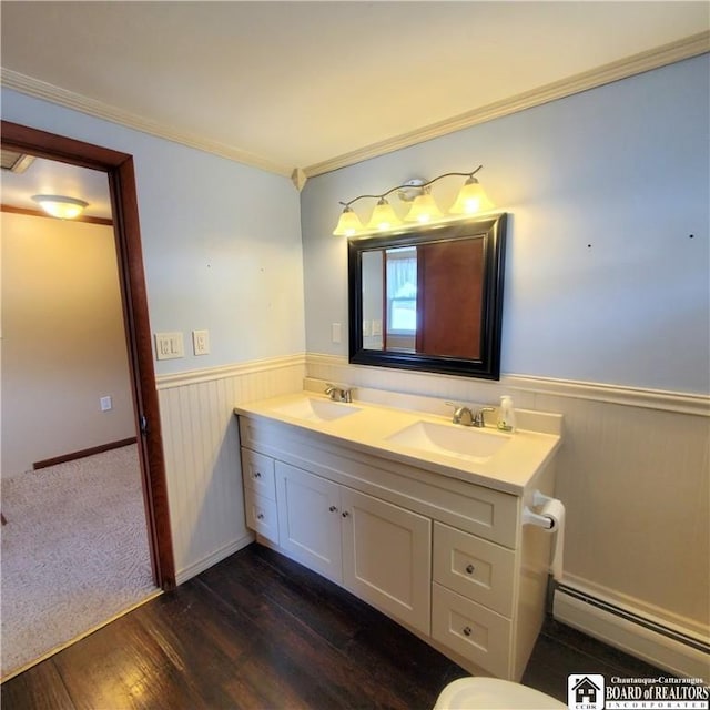 bathroom with a baseboard radiator, ornamental molding, hardwood / wood-style floors, and vanity