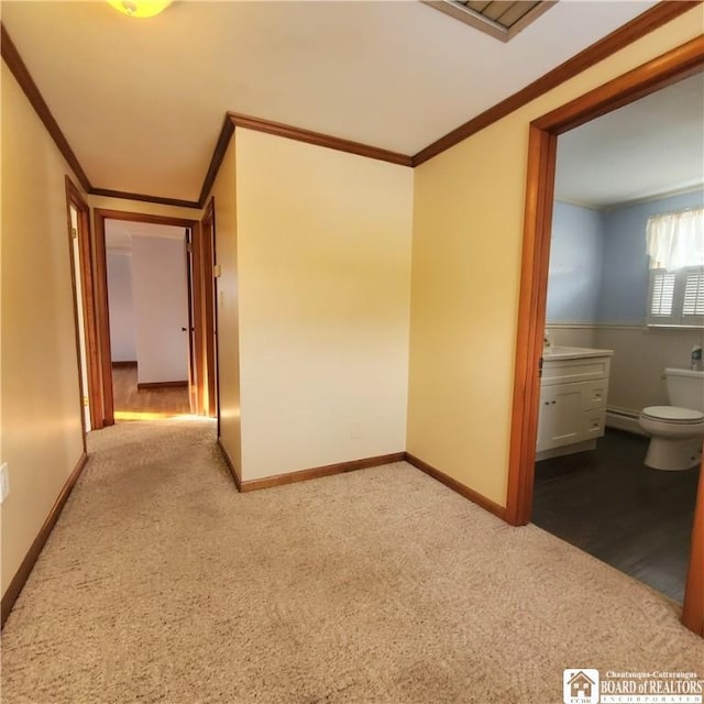 unfurnished bedroom featuring light colored carpet, ornamental molding, and baseboard heating