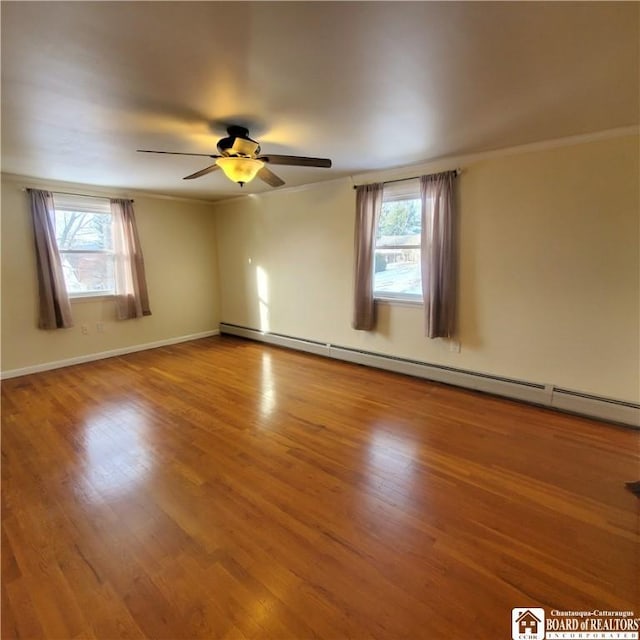 unfurnished room with crown molding, ceiling fan, wood-type flooring, and a baseboard heating unit