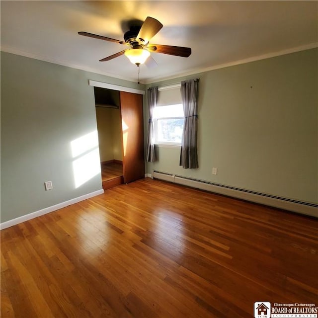 empty room with ceiling fan, ornamental molding, wood-type flooring, and a baseboard heating unit