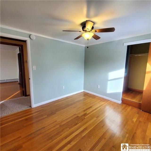 unfurnished bedroom featuring hardwood / wood-style floors, a baseboard radiator, ornamental molding, and ceiling fan