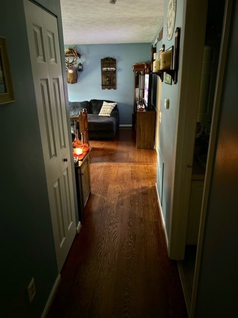 corridor with dark hardwood / wood-style flooring and a textured ceiling