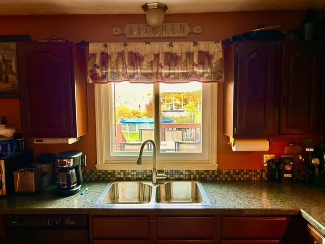 kitchen featuring tasteful backsplash, sink, and dishwashing machine