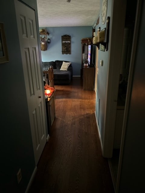 hall with dark hardwood / wood-style flooring and a textured ceiling