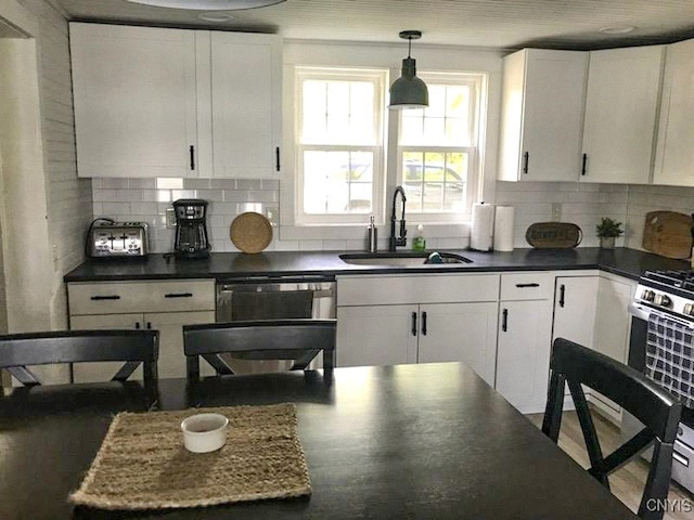 kitchen with stainless steel appliances, sink, tasteful backsplash, decorative light fixtures, and white cabinets