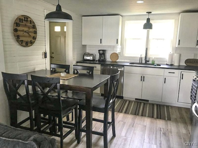 kitchen with dishwasher, hanging light fixtures, sink, and white cabinets