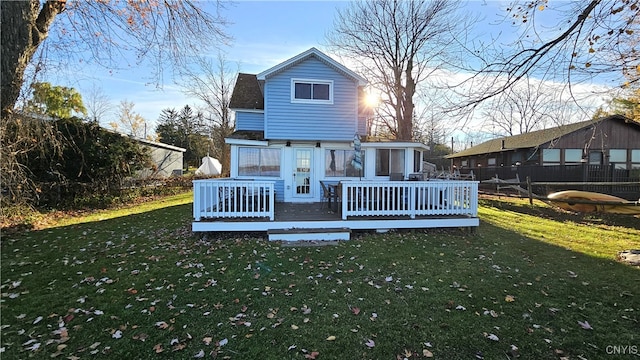 rear view of house featuring a wooden deck and a lawn