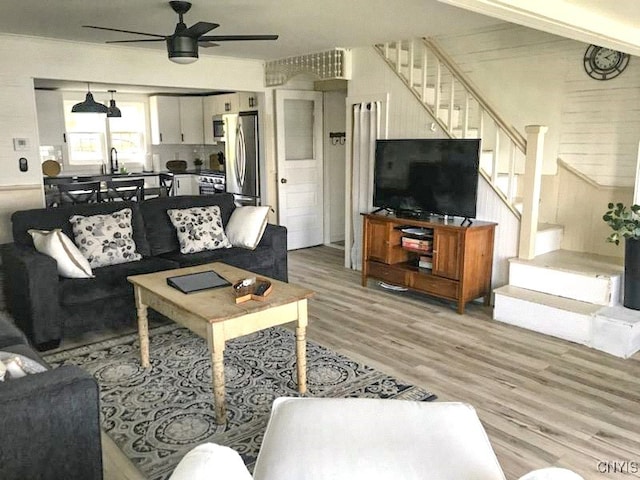 living room featuring light hardwood / wood-style floors, ceiling fan, and sink