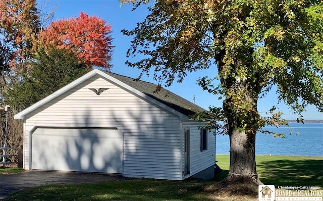 view of side of property featuring an outbuilding, a garage, a water view, and a lawn