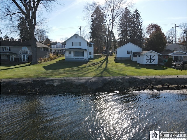 exterior space featuring a water view, a shed, and a yard