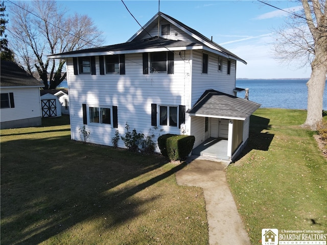 view of front facade featuring a front lawn, a shed, and a water view