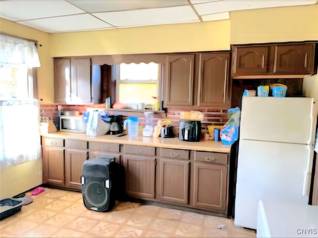 kitchen featuring a drop ceiling and white fridge