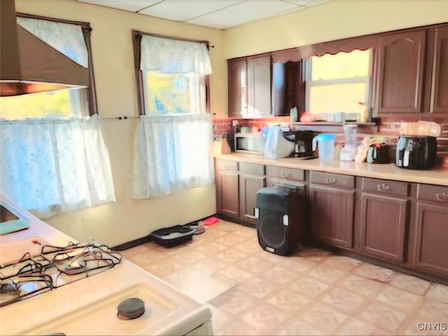 kitchen with dark brown cabinets, a paneled ceiling, and white stove