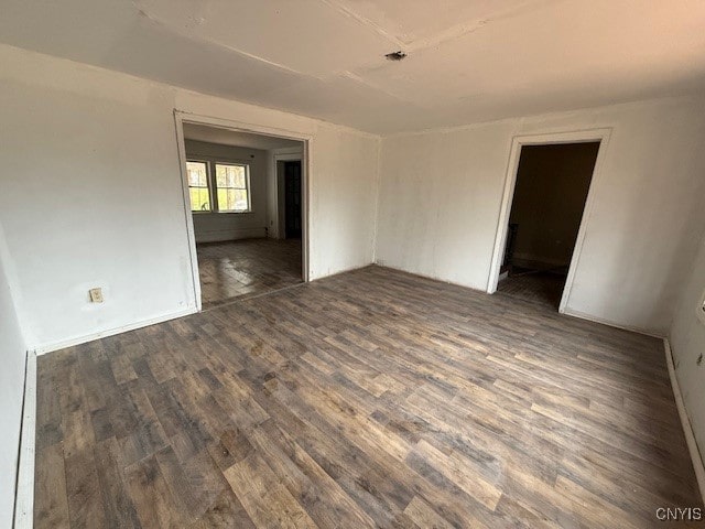 unfurnished room with dark hardwood / wood-style floors and a baseboard heating unit