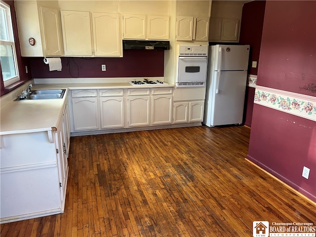 kitchen with white appliances, white cabinetry, sink, and dark hardwood / wood-style flooring