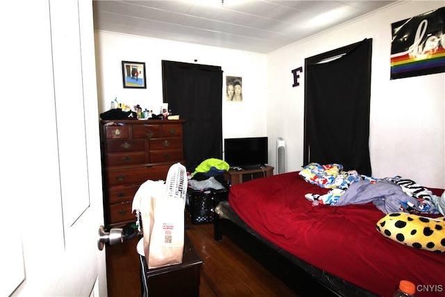 bedroom featuring ornamental molding and dark hardwood / wood-style flooring